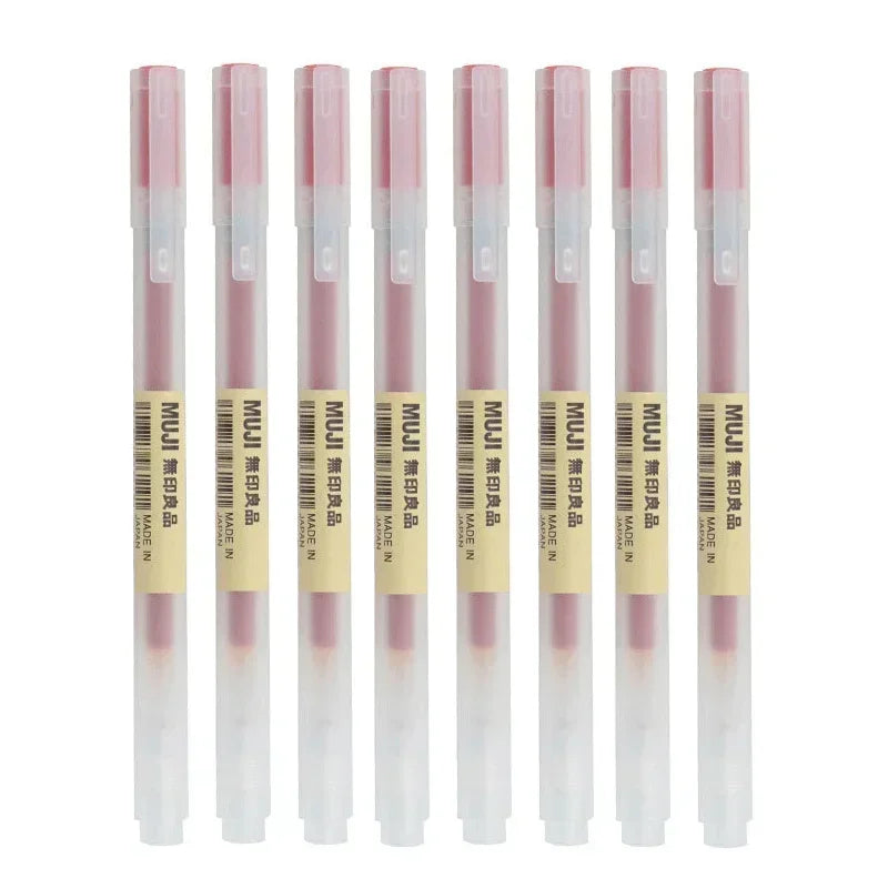 Set of eight MUJI pens with pink caps on a white background