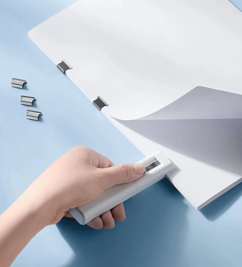Hand using bentopop metal paper clipper to bind some papers on a light blue background