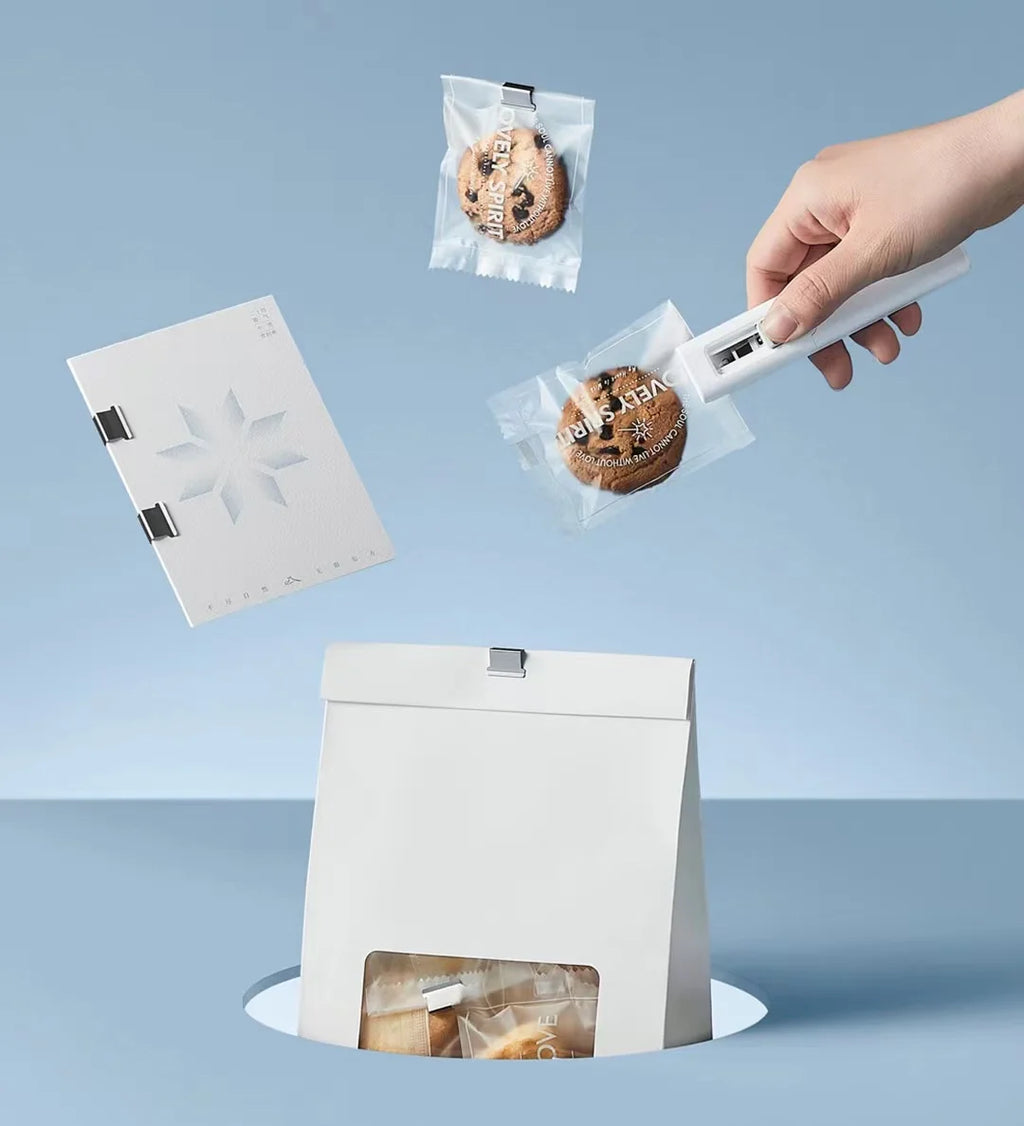 Person using a bentopop paper clipper to close a cookie bag with a blue background