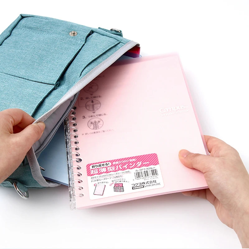 Person holding a pink notebook with a blue cover against a white background