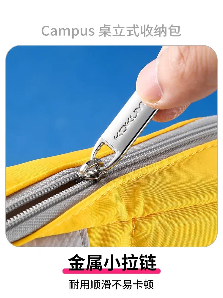 Bentopop  yellow and gray stationery bag kokuyo campus with metal zipper being pulled open, against a blue background.