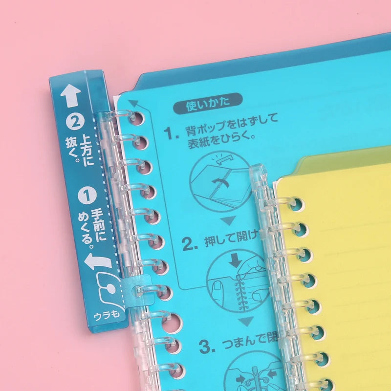 Clear spiral notebook with blue and yellow covers on a pink background